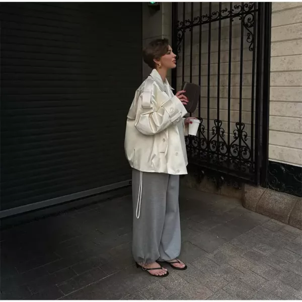 Model wearing an ivory cropped satin trench jacket with a black turtleneck.