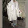 Model wearing an ivory cropped satin trench jacket with a black turtleneck.