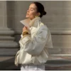 Model wearing an ivory cropped satin trench jacket with a black turtleneck.