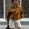 Model wearing a cropped suede bomber jacket with puff sleeves in a rich camel color