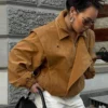 Model wearing a cropped suede bomber jacket with puff sleeves in a rich camel color