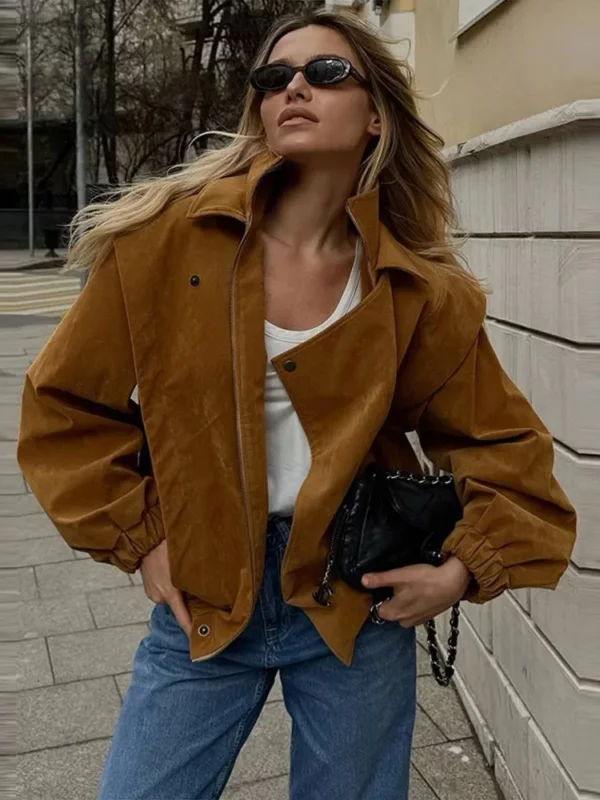 Model wearing a cropped suede bomber jacket with puff sleeves in a rich camel color