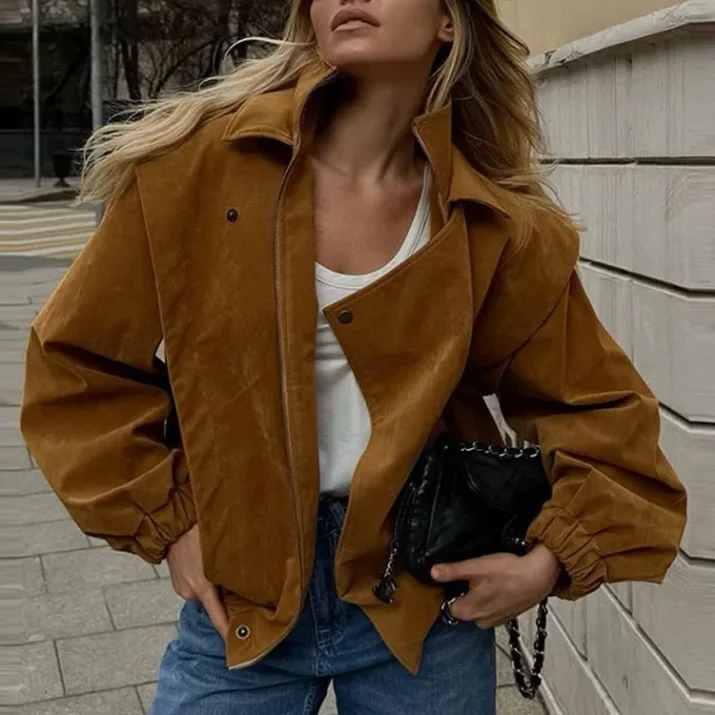 Model wearing a cropped suede bomber jacket with puff sleeves in a rich camel color