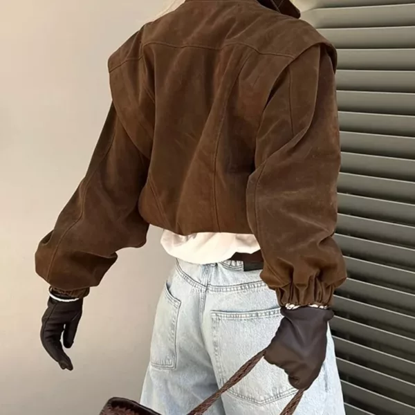 Model wearing a cropped suede bomber jacket with puff sleeves in a rich brown color