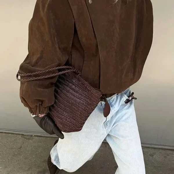 Model wearing a cropped suede bomber jacket with puff sleeves in a rich brown color