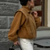 Model wearing a cropped suede bomber jacket with puff sleeves in a rich camel color
