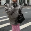 Model wearing an oversized trench coat with a wide lapel and belted hem.