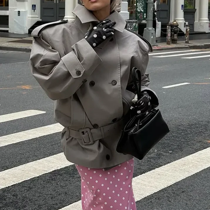 Model wearing an oversized trench coat with a wide lapel and belted hem.