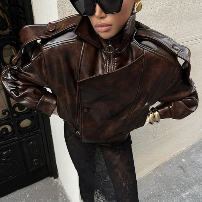 Model wearing glossy brown leather jacket paired with black lace skirt for chic look.